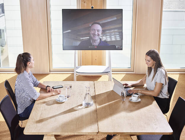Mitarbeiterinnen in Meetingraum mit großem Bildschirm Telefonkonferenz in modernem Bürogebäude - Businessfotograf Businessfotografie Christian Vorhofer