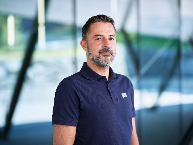 Businessportrait Mann im blauen Poloshirt und vor Glasgebäude - Businessfotograf Businessfotografie Christian Vorhofer