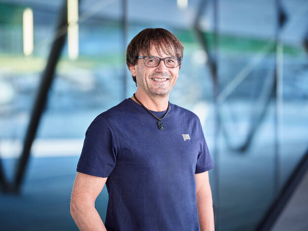 Businessfoto Mitarbeiter blaues T-Shirt vor Glasfront - Businessfotograf Businessfotografie Christian Vorhofer