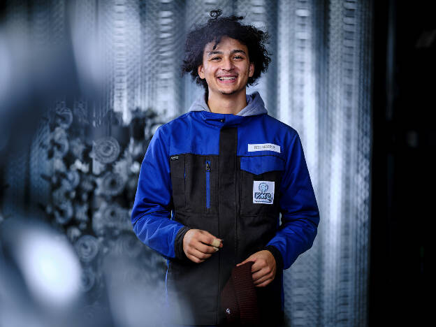 Unternehmensfoto Mitarbeiterkampagne Mann in blau schwarz vor silbernen Maschinen - Businessfotograf Businessfotografie Christian Vorhofer