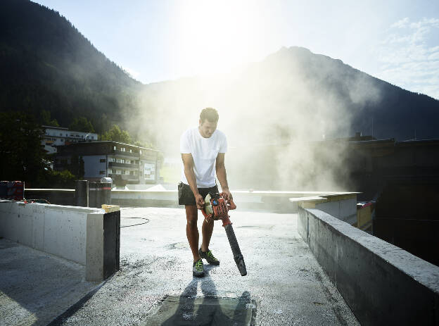 Schwarzdecker mit Akkugebläse säubert Dach vor Arbeitsbeginn, Industreifotograf Christian Vorhofer, Kunde WKO Tirol