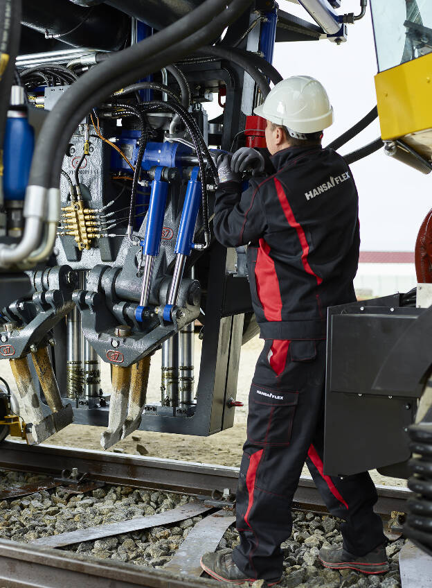 Detailansicht einer Gleisbaumaschine, system7, Montauer-Techniker befestigt Hydraulikschläuche, Industriefotografie Christian Vorhofer, Kunde Hansaflex