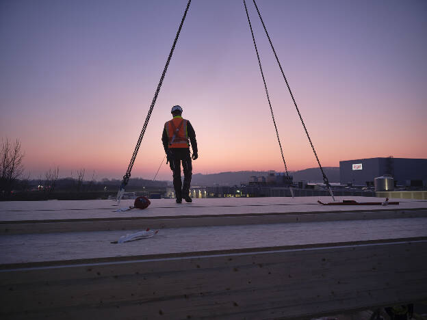 Zimmermann mit Sicherungsgurt am Dach bei Abenddämmerung, Industriefotografie Christian Vorhofer, Kunde Egger