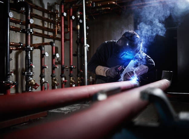 Schweißarbeiten im Technikraum, Heizraum, Gebäudetechnik, Installateur bei Schweißarbeiten, Industriefotografie Christian Vorhofer, Kunde KGT-Gebäudetechnik