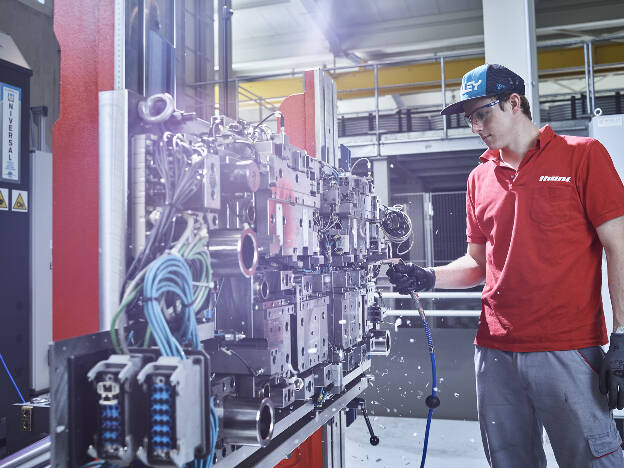 Mitarbeiter entfernt mit Druckluft Metallspäne, Maschinenbau, Metallverarbeitung, Anlage, Industriefotografie Christian Vorhofer, Kunde Thöni