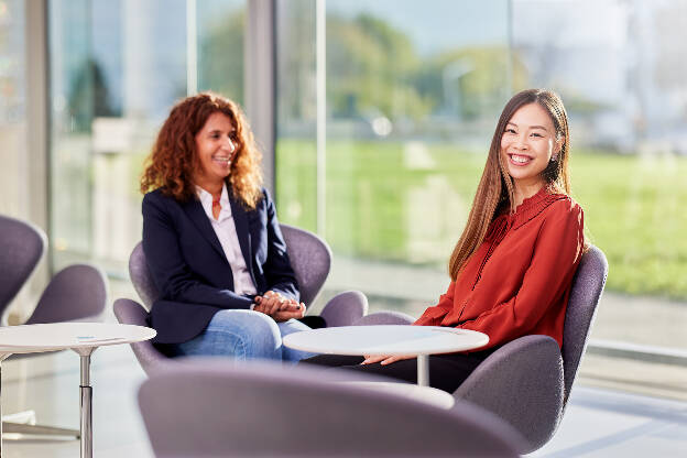 Unternehmensfoto Unternehmensfotografie zwei asiatische Frauen sitzen lachend an einem runden Tisch - Businessfotograf Businessfotografie Christian Vorhofer