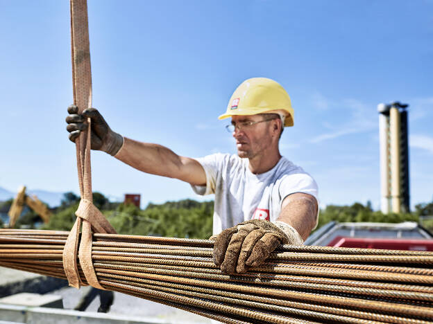 Arbeiter hebt Baueisen mit Baustellenkran, Industriefotografie Christian Vorhofer, Kunde Rhomberg Bau