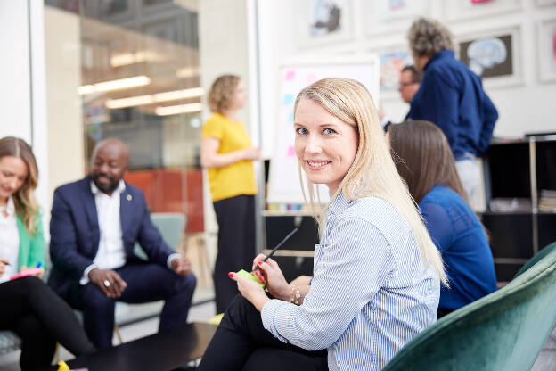 Frau schaut in Kamera Hintergrund Meeting Employer Branding - Businessfotograf Businessfotografie Christian Vorhofer