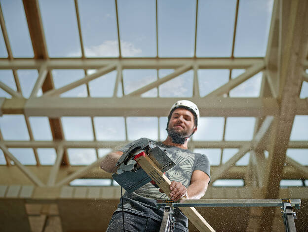 Zimmermann schneidet Holzleiste mit Handkreissäge, Baustelle, Holzbaukonstruktion, Industriefotografie Christian Vorhofer, Kunde Egger