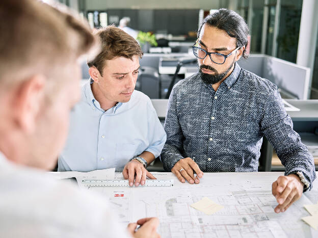 Unternehmensfoto Unternehmensfotografie drei Mitarbeiter sehen sich einen Bauplan im Büro an - Businessfotograf Businessfotografie Christian Vorhofer